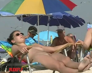 Chesty female sunbathing in a naked beach